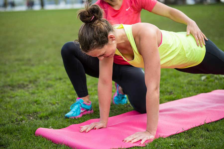 Sportlerin im Haltestütz wird von einer Personal Trainerin angeleitet