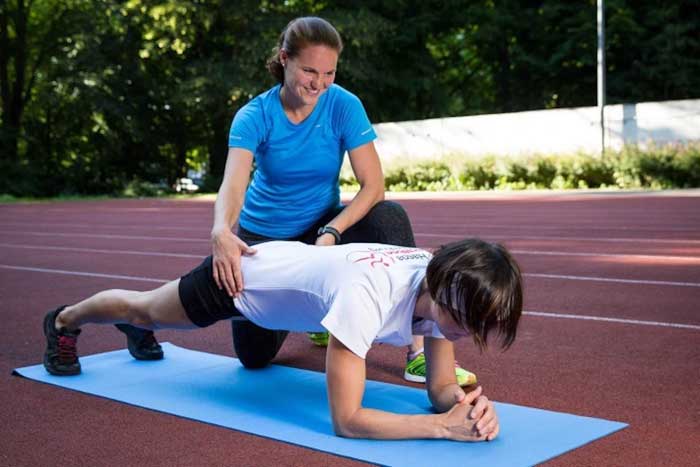 Sportlerin im Haltestütz wird von Personal Trainerin korrigiert