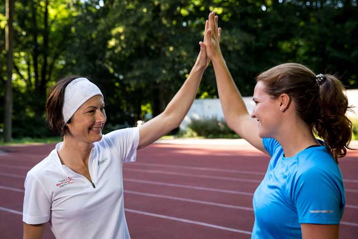 Sportlerin und Personal Trainerin klatschen nach erfolgreichem Lauftraining ab