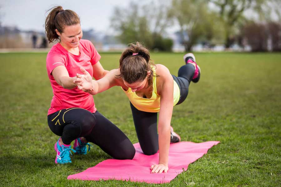 Sportlerin im Haltestütz wird von einer Personal Trainerin angeleitet